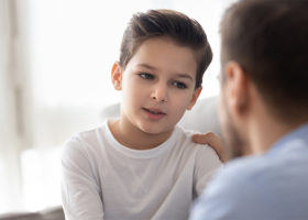Omtänksam pappa pratar med lille son och visar kärlek och stöd