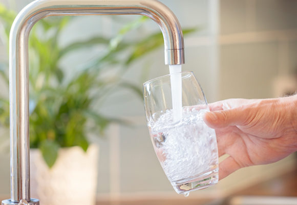 Vattenglas fylls på med vatten från kran