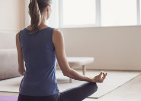 Kvinna syns yoga i skräddarställning bakifrån