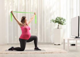 gravid kvinna tränar framför teven