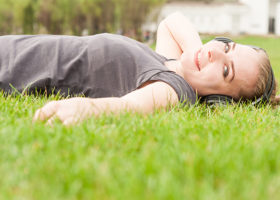 Kvinna ligger i gräset och lyssnar med lurar på
