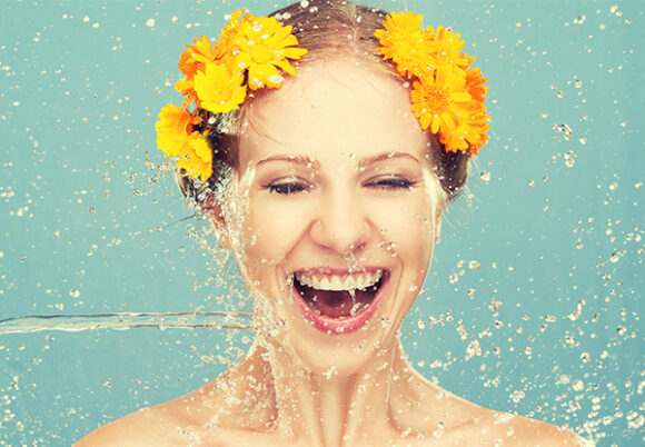 Kvinna med gula blommor i håret får vatten stänkt på sig