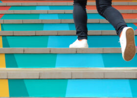 Ett par ben som går i färgglada trappor