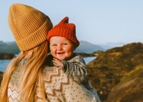 Mamma med bebis i famnen i fjällandskap
