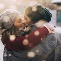 Man och kvinna kysser varandra i snöfall