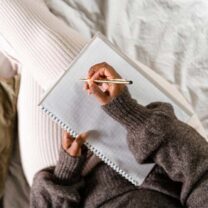 Kvinna i säng gör anteckningar på papper