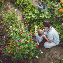 Kvinna och litet barn i blommande trädgård