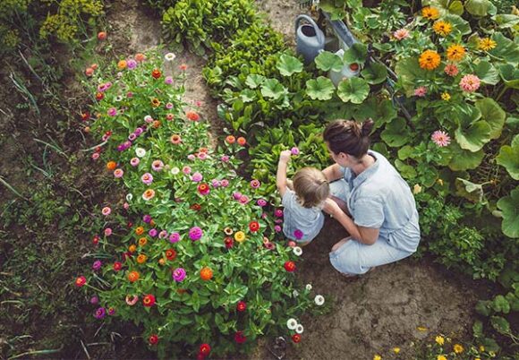 Kvinna och litet barn i blommande trädgård
