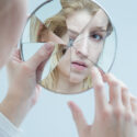Kvinna ser på sig själv i trasig spegel