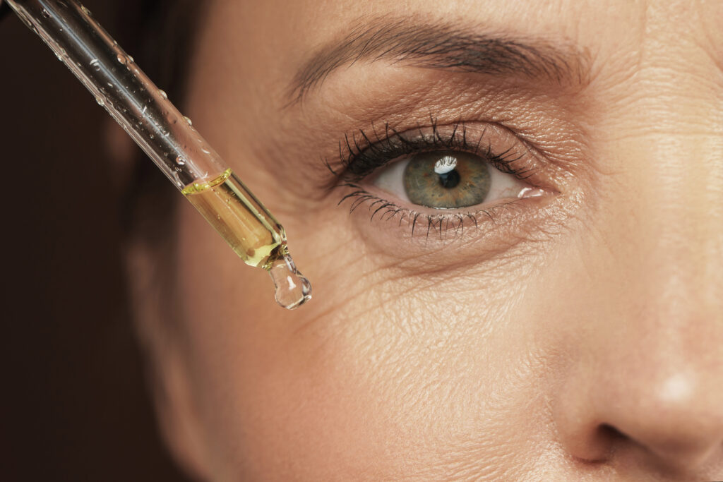 Närbild på serum som droppas med pipett i kvinnoansikte