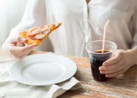 Närbild på kvinna ätande pizza och dricker läsk