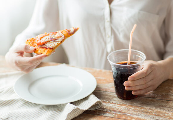 Närbild på kvinna ätande pizza och dricker läsk