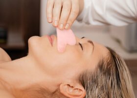 Kvinna får gua sha-behandling med rosa sten