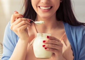 Närbild på ung kvinna som äter yoghurt