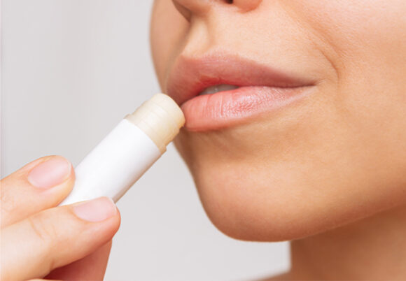 Närbild på kvinna som applicerar cerat på läpparna