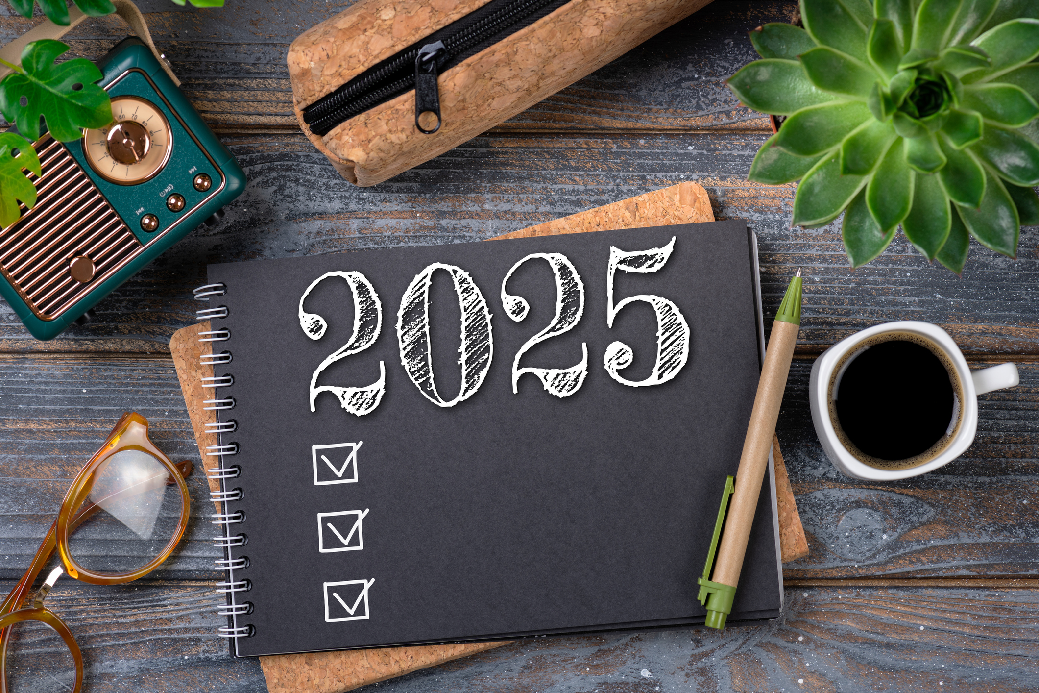 New year resolutions 2025 on desk. 2025 goals list with notebook, coffee cup, plant on wooden table. Resolutions, plan, goals, action, checklist, idea concept. New Year 2025 resolutions, copy space