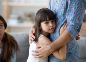 Liten flicka håller om midjan på sin pappa