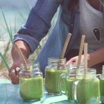 Gröna smoothies på dukat bord på strand