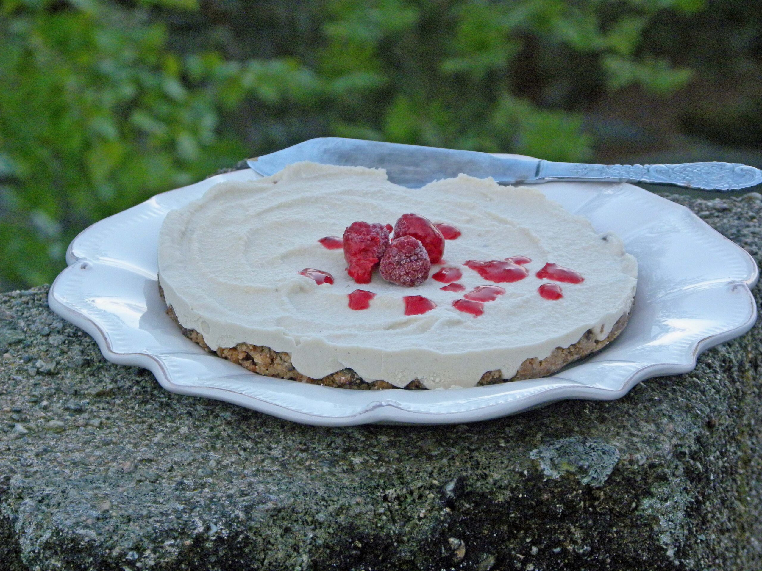 Cheesecake rawfood på ett vitt fat som står på en stenpelare