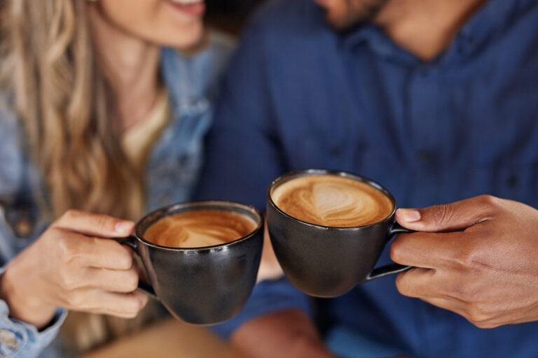 Love, coffee and hands of couple in cafe for celebration, valentines day and romance date. Latte, art and relax with man and woman in restaurant for retail, bonding and quality time together