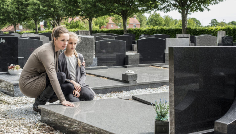Mor och dotter besöker en grav på en kyrkogård