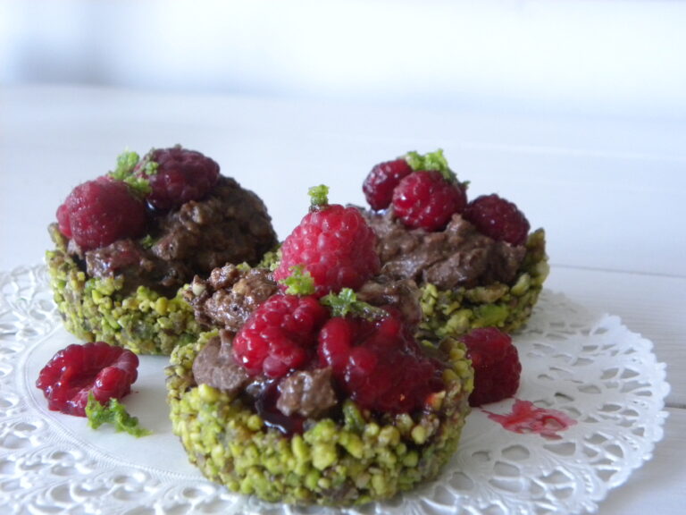 Små gröna spistagebakelser med mintchokladmousse, toppade med hallon