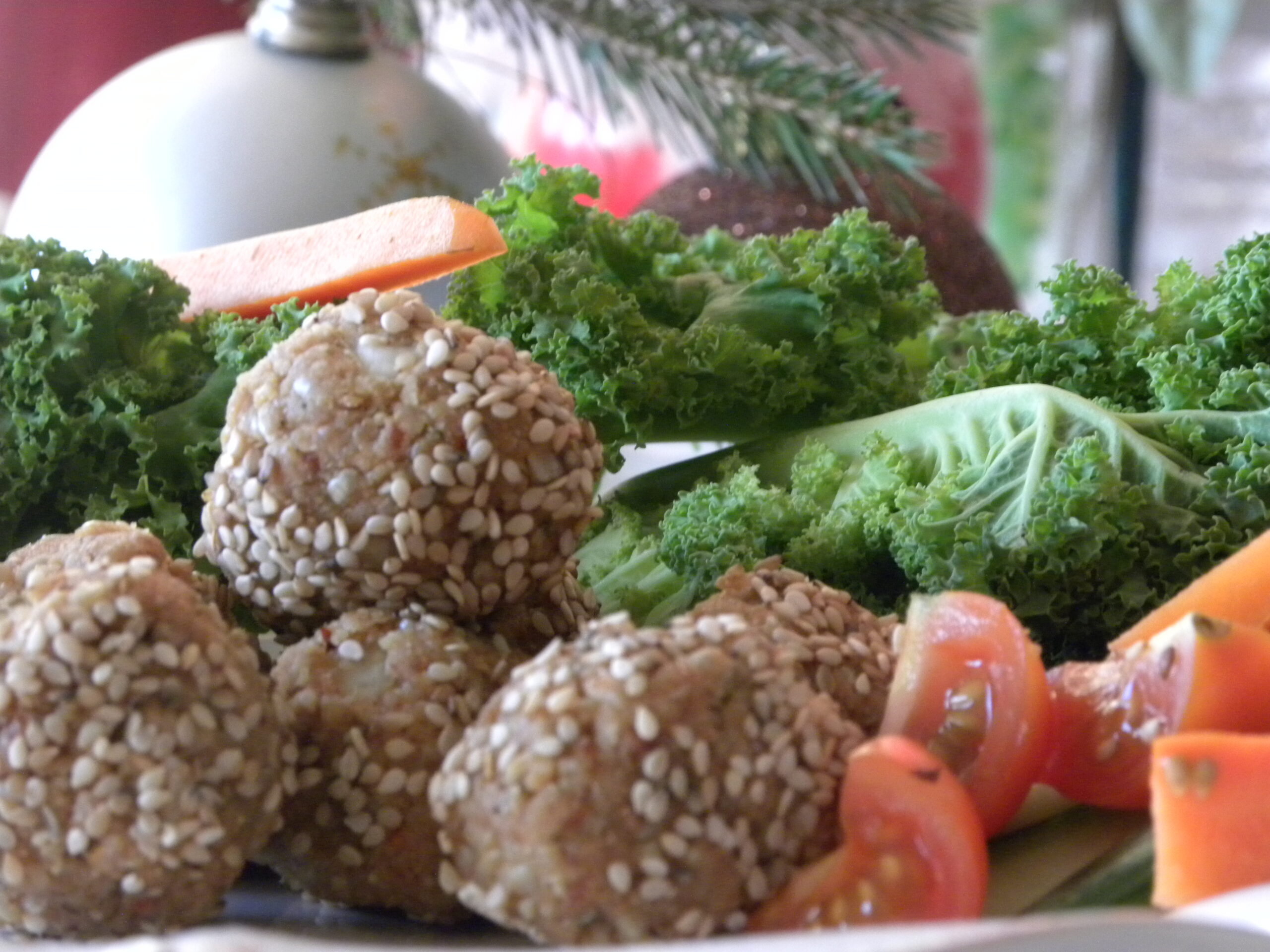 Rawfood solrosfröbollar på ett fat med grönkål och andra grönsaker