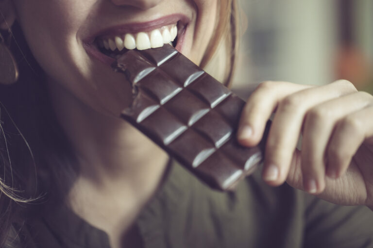 Närbild på kvinna som äter mörk choklad