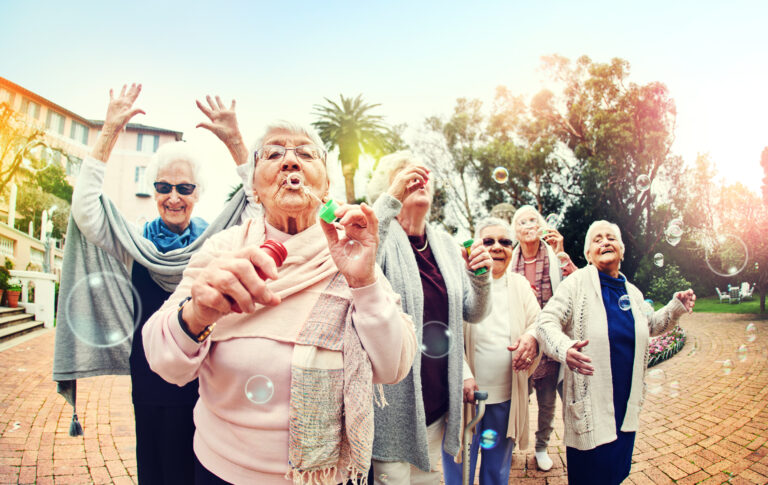En grupp glada äldre kvinnor som blåser s