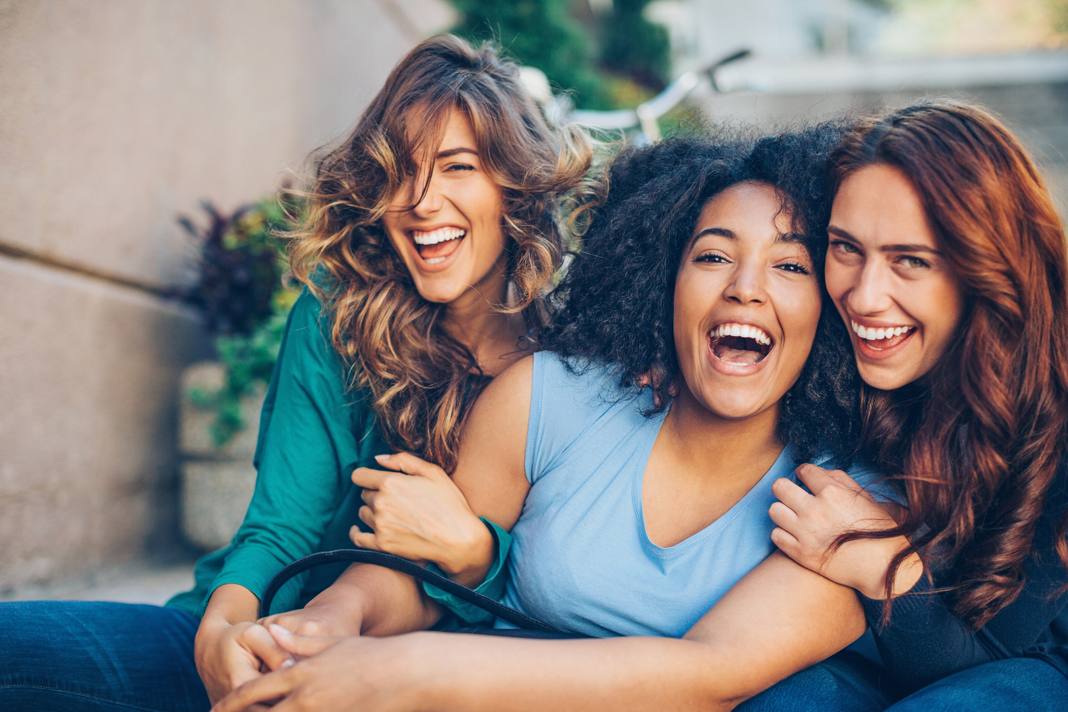 Tre skrattande kvinnor håller om varandra