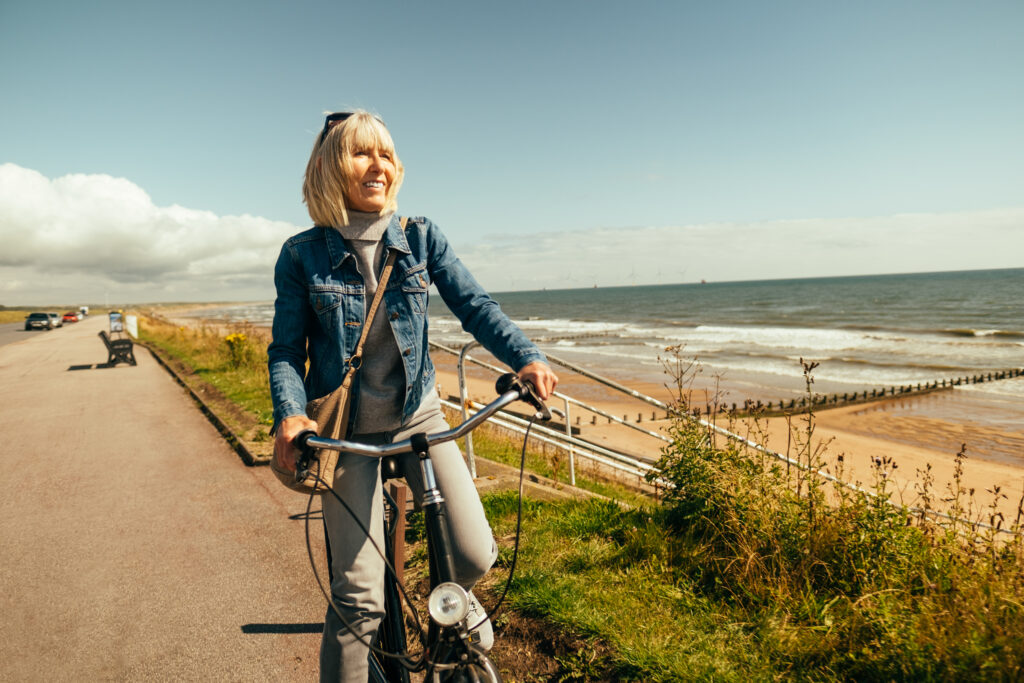 Kvinna cyklar längs stranden