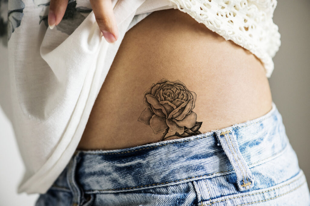 Närbild på en tatuering i form av en ros på en kvinnas höft