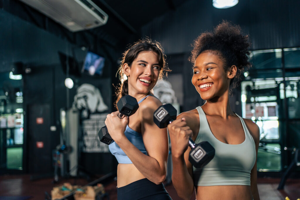 Två unga kvinnor tränar med hantlar på gym