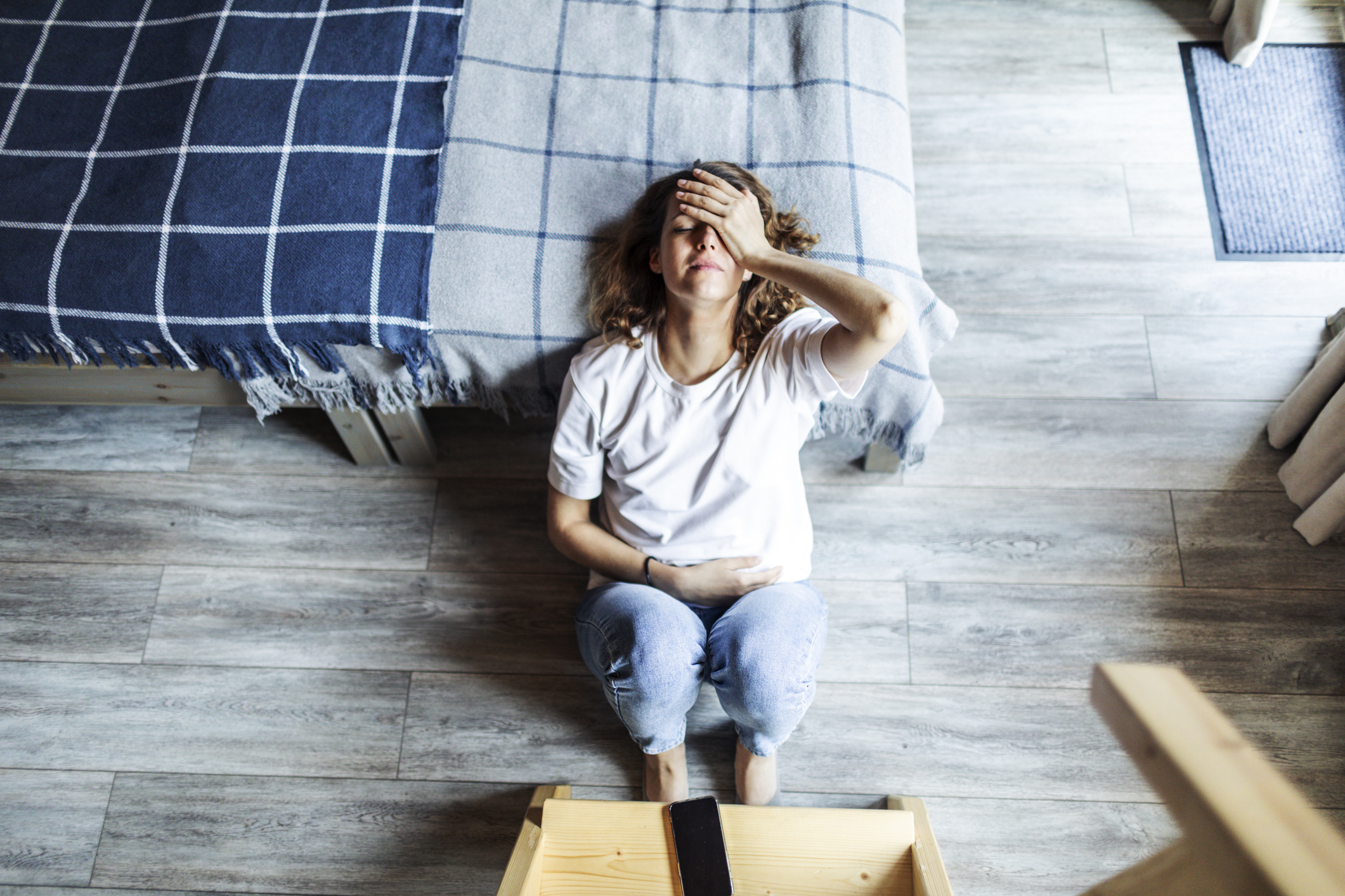 Young adult woman with depression sitting at home alone