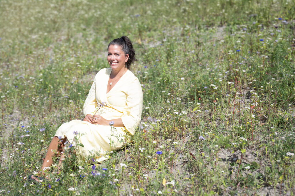 Sari Nieminen sittande i en blomstrande äng