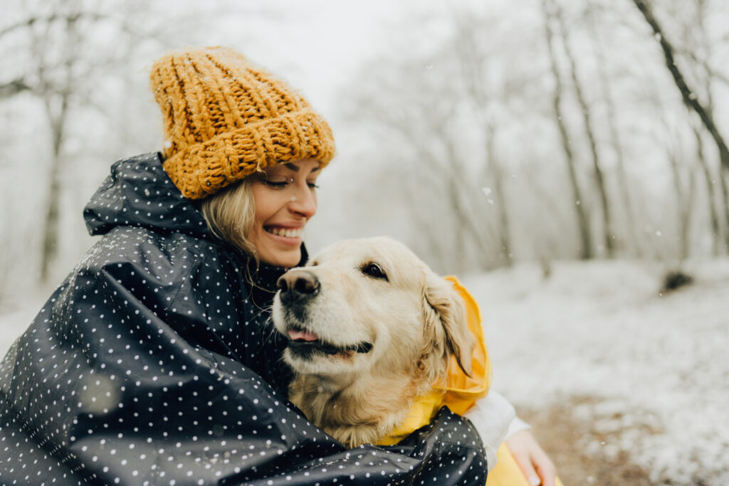 Glad kvinna med sin hund en snöig dag