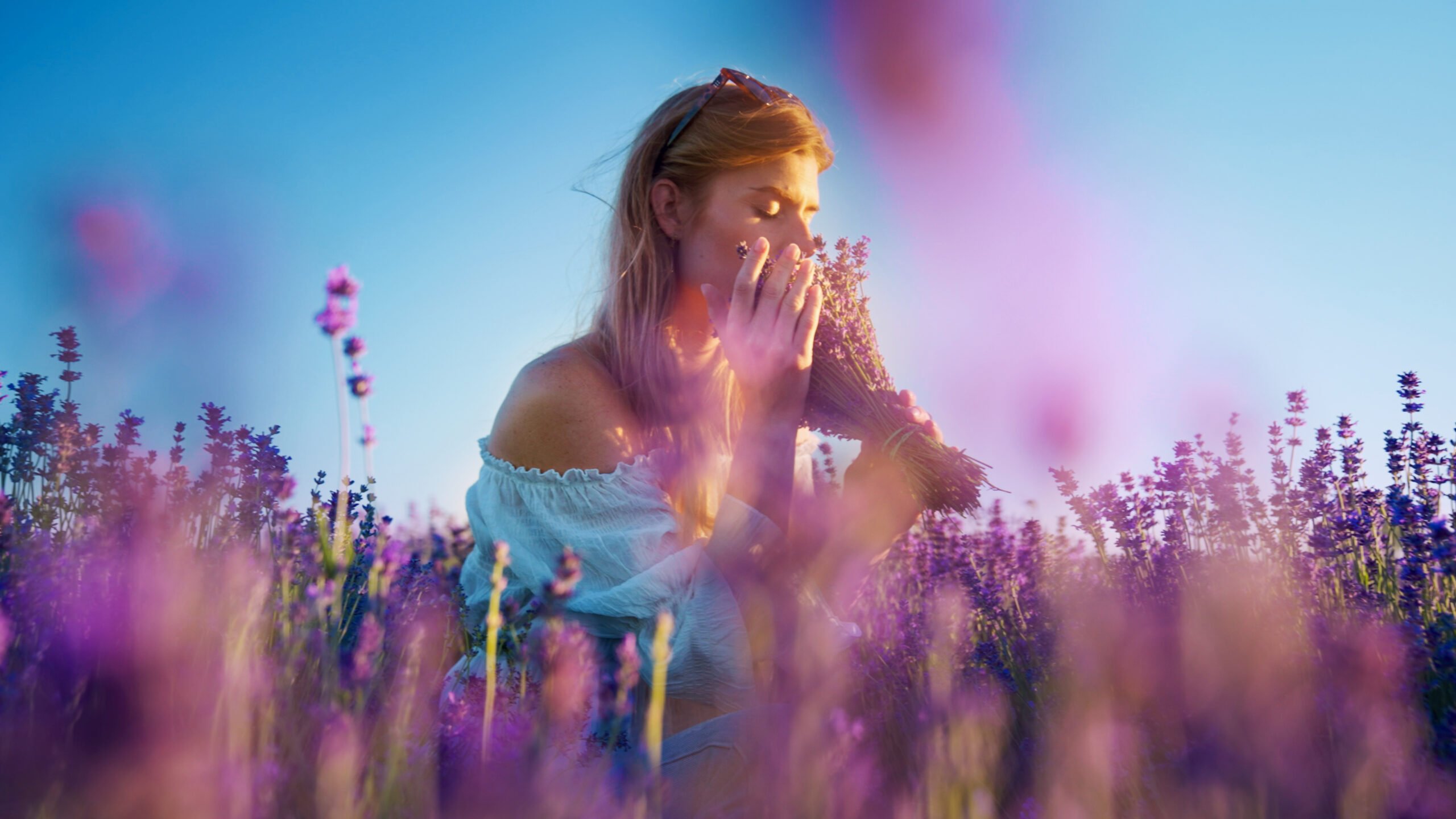 Ung kvinna doftar på lavendel i en trädgård