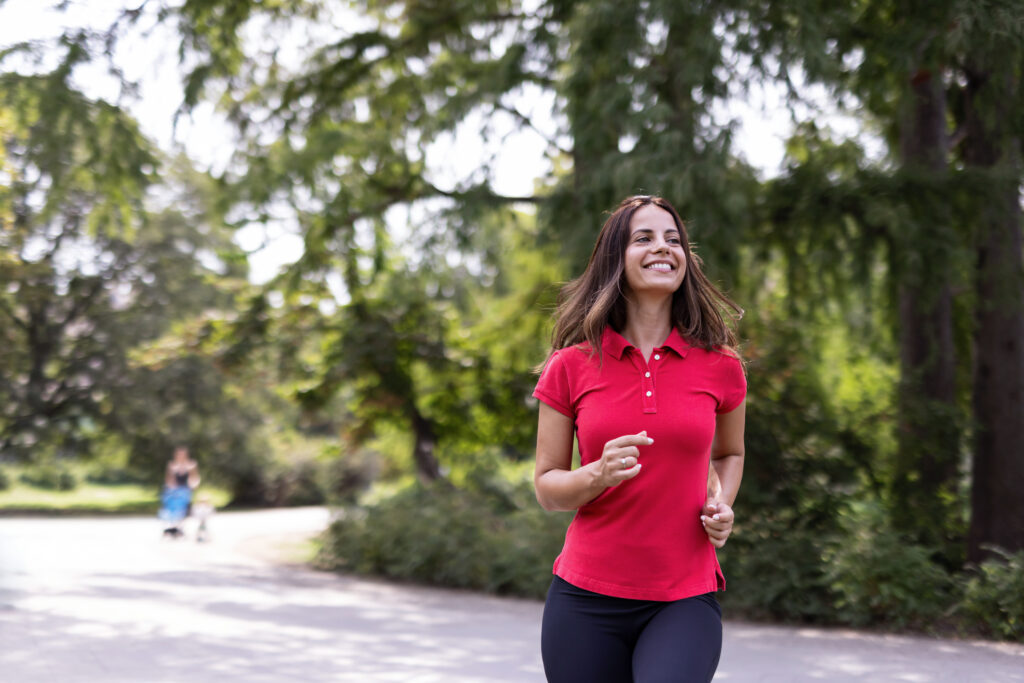 Lycklig kvinna promenerar/joggar i park