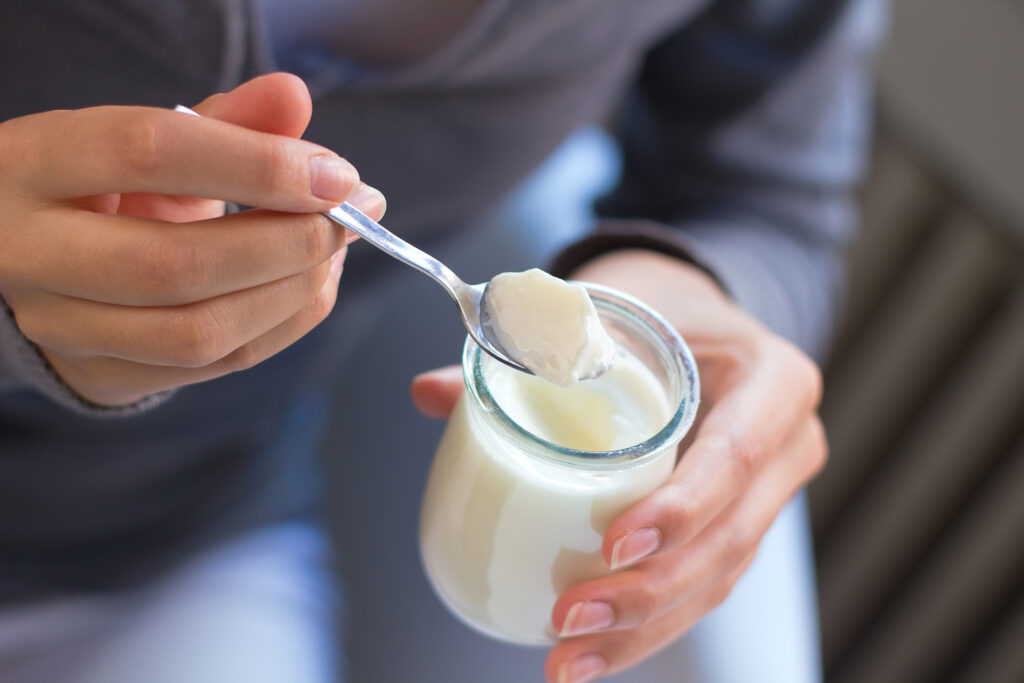 Närbild på kvinna som äter yoghurt ur glasburk