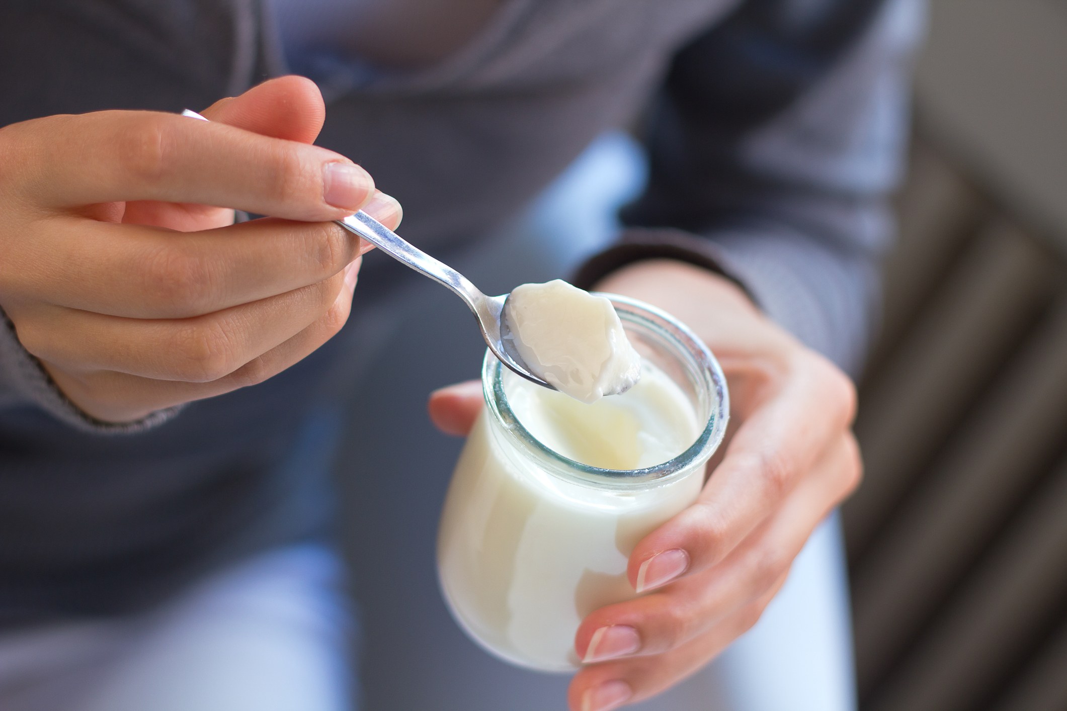 Närbild på kvinna som äter yoghurt ur glasburk