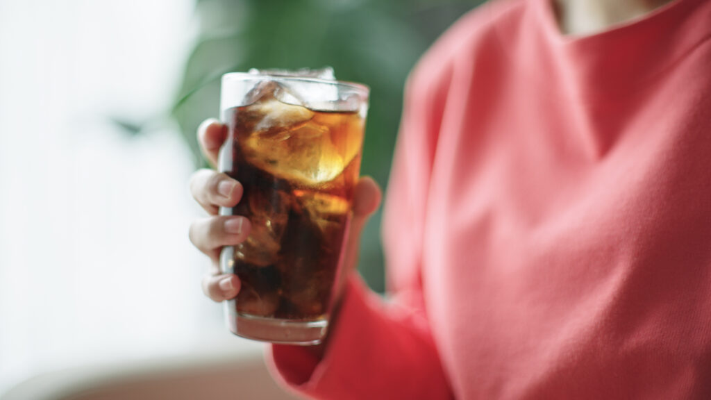 Närbild på kvinna som håller i ett glas cola med is