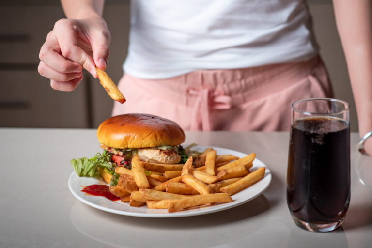 Närbild på kvinna som äter hamburgare och pommes frites