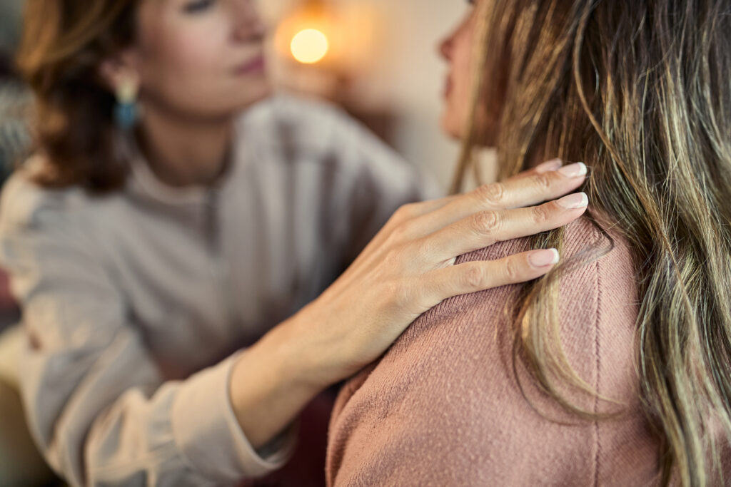 En kvinna stöttar en annan, men handen på hennes axel