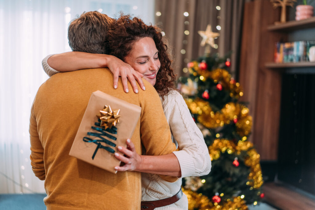 Par som omfamnar varandra framför julgranen