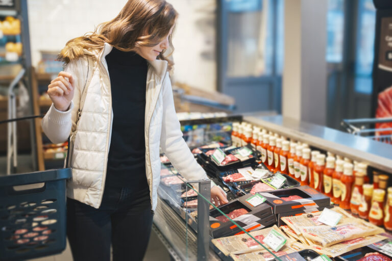 Kvinna i matbutik framför charkuterier