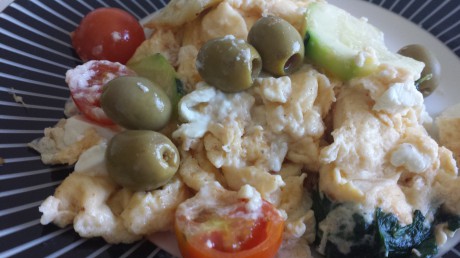 Omelett med tomat, zucchini, spenat, fetaost och oliver på fat som är vitsvart randigt