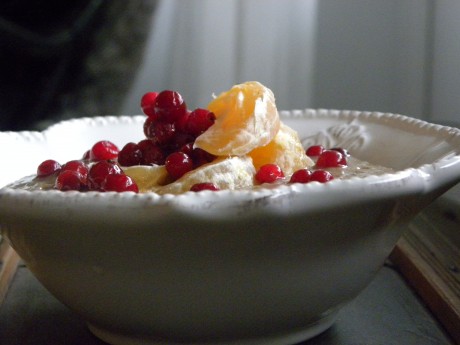 Chiapudding toppad med klementinklyftor och lingon i en vit djup tallrik på ett brunt bord