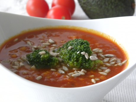 Tomat och linssoppa toppad med broccoli och solrosfrön i en vit djup skål