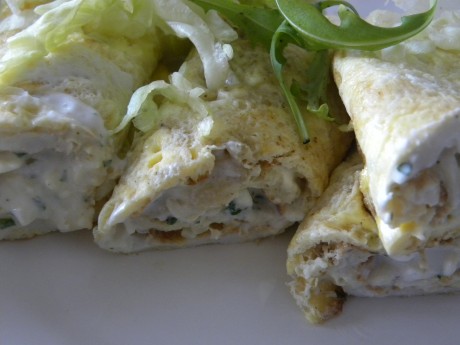 Fyllad omelettrullar på ett vitt fat, toppade med grön sallad
