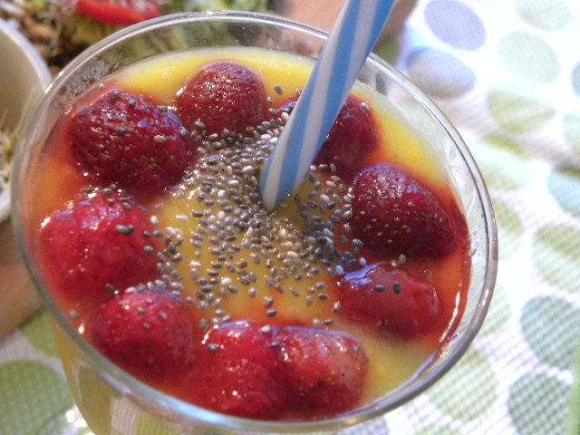 Smoorhie emd mango, apelsin och ingefära toppad med jordgubbar och chiafrön i ett glas